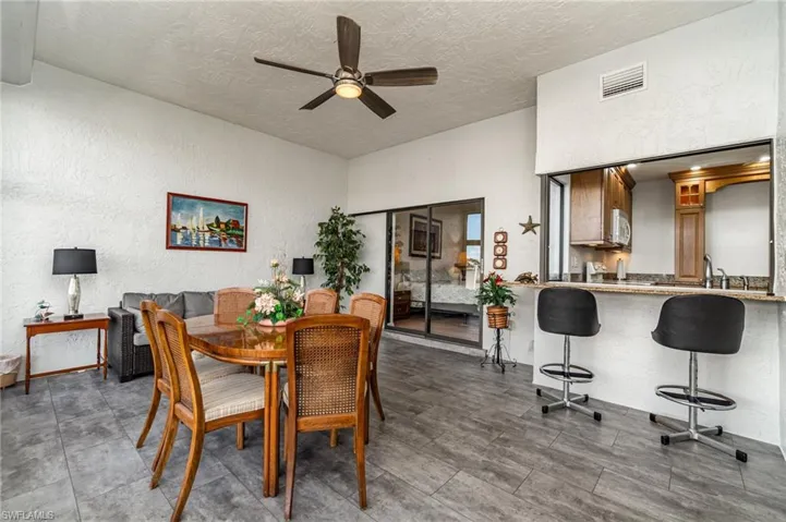 Sunroom featuring a textured wall, a ceiling fan, and a textured ceiling