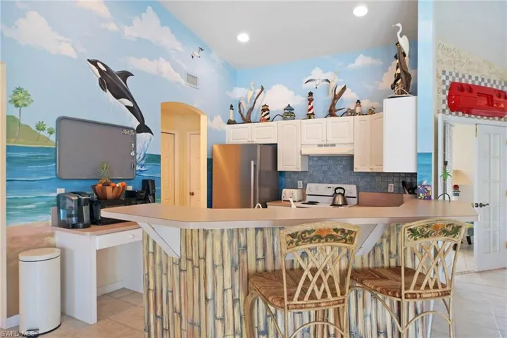 Kitchen features all appliances, desk/work station, a peninsula/dining bar, and tropical decor