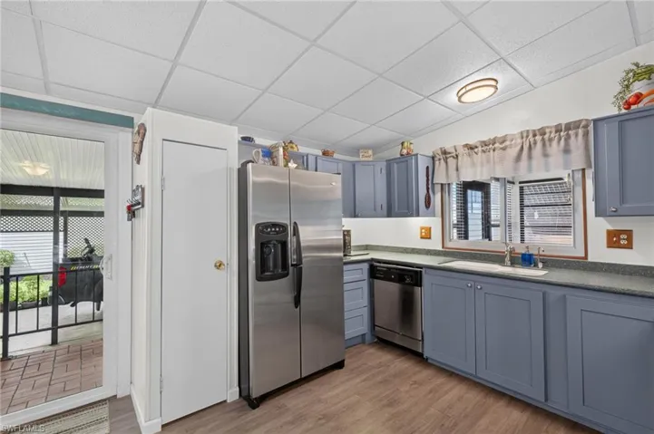 Kitchen featuring blue cabinetry, stainless steel appliances, a single-basin sink, and wood-finish flooring