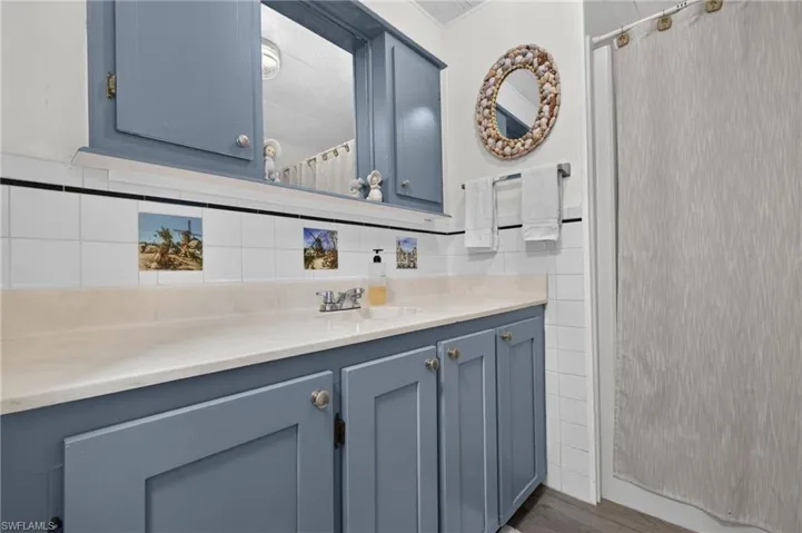 Guest Bathroom featuring custom cabinetry with hardware, a light stone countertop, and an illuminated medicine cabinet with mirrored front