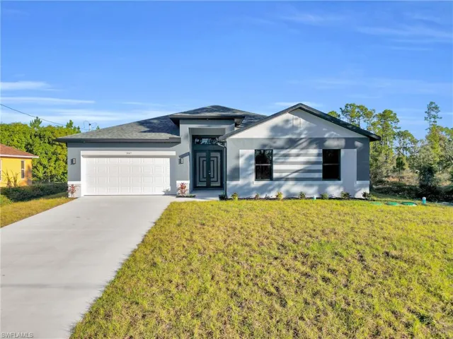 View of front facade featuring concrete driveway, stucco siding, an attached garage, and a front yard