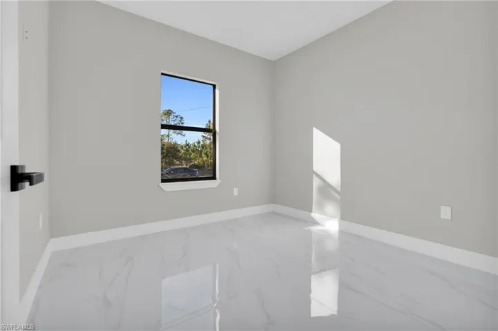 Empty room featuring marble look tile flooring and baseboards