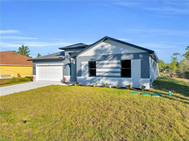 View of front of home featuring a front yard, driveway, stucco siding, and an attached garage
