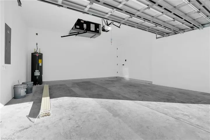 Garage with water heater, electric panel, and a garage door opener