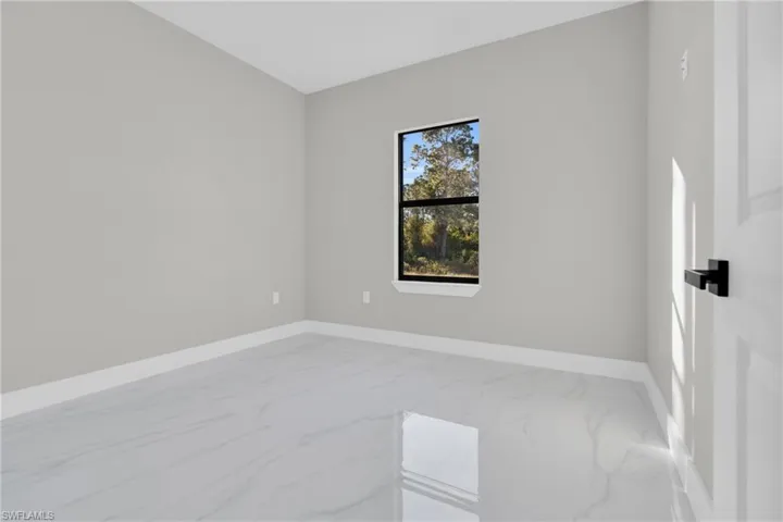 Unfurnished room featuring baseboards and light marble finish flooring