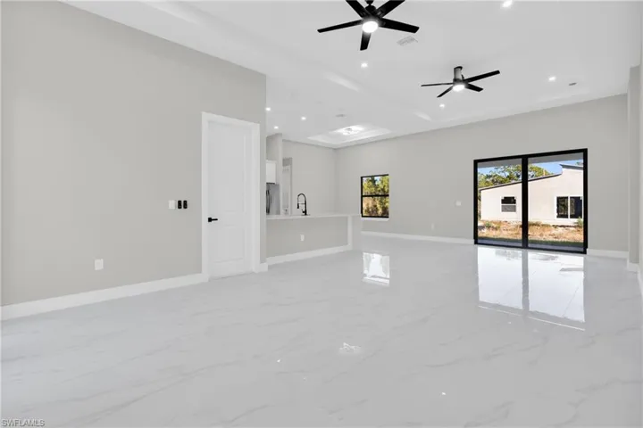 Unfurnished room with light marble finish floors, a ceiling fan, recessed lighting, and a tray ceiling