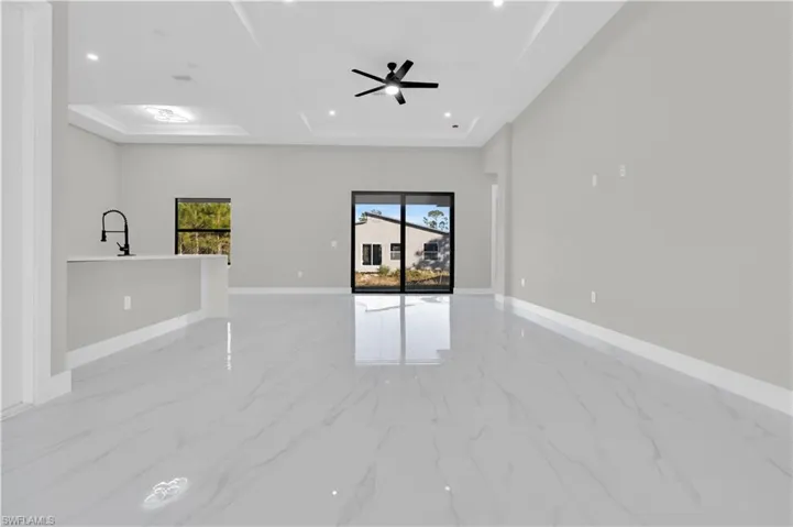 Empty room with light marble finish flooring, a raised ceiling, a ceiling fan, and recessed lighting