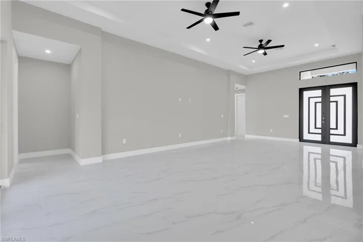 Unfurnished room with recessed lighting, light marble finish flooring, a ceiling fan, a tray ceiling, and french doors