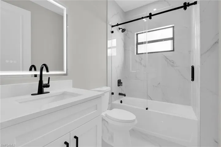 Bathroom featuring vanity, enclosed tub / shower combo, and marble finish flooring