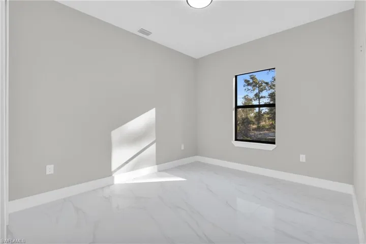 Unfurnished room with marble look tile flooring and baseboards