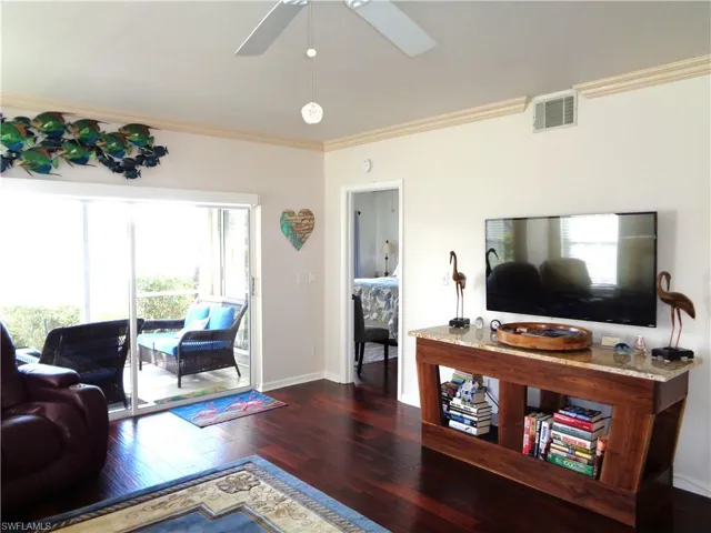 Living area with wood-type flooring, ornamental molding, and ceiling fan