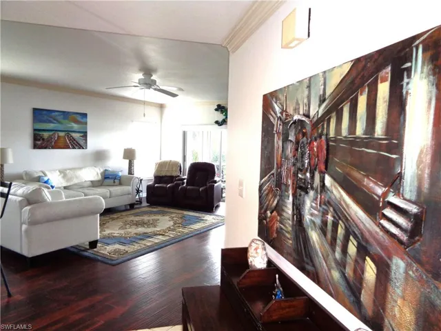 Living area with crown molding, a ceiling fan, and wood finished floors