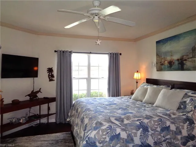 Bedroom with crown molding, wood finished floors, and ceiling fan