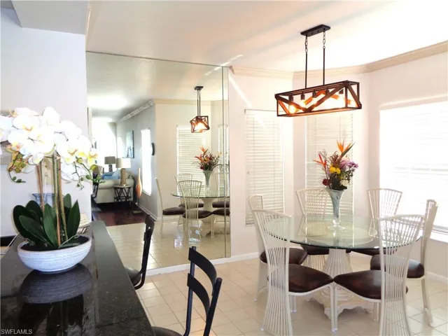 Tiled dining area featuring crown molding and a chandelier