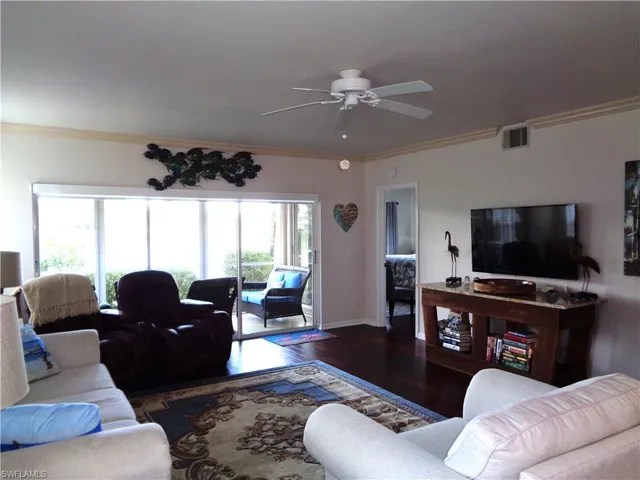 Living area with wood finished floors, ceiling fan, and ornamental molding