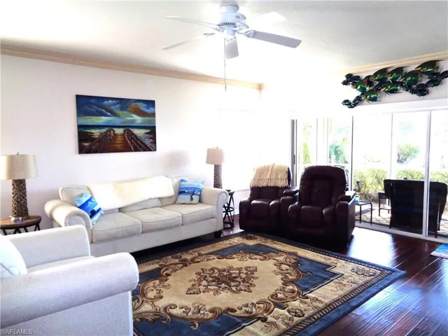 Living room featuring wood finished floors, ceiling fan, and crown molding