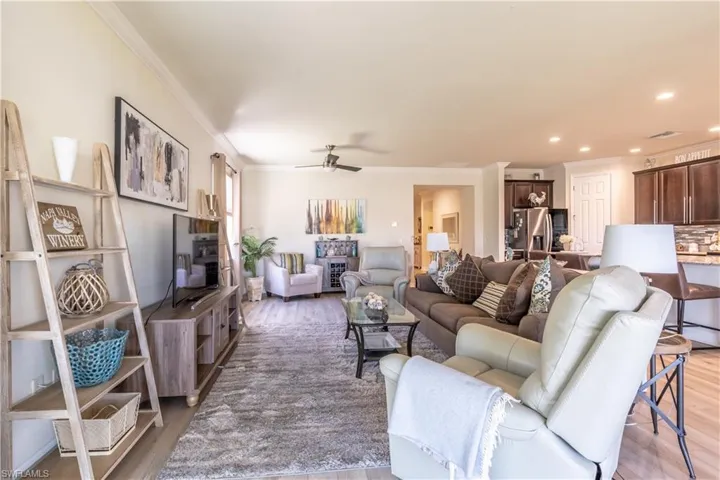 Living room featuring ornamental molding, wood-type flooring, and ceiling fan
