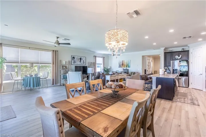 Dining space featuring crown molding, light hardwood / wood-style flooring, and ceiling fan with notable chandelier