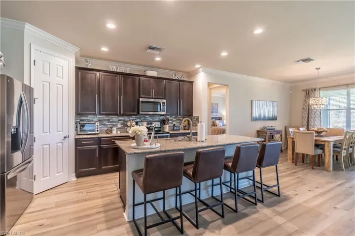 Kitchen featuring sink, stainless steel appliances, decorative light fixtures, light hardwood / wood-style flooring, and a kitchen island with sink