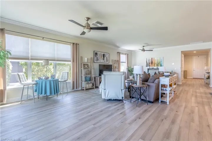 Living room with ornamental molding, light hardwood / wood-style flooring, and ceiling fan