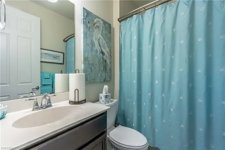 Bathroom with vanity, a shower with curtain, and toilet