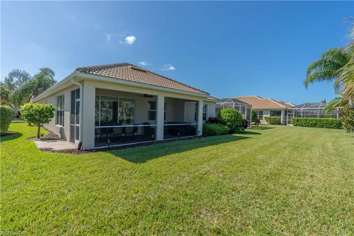 Rear view of house with a lanai and a lawn