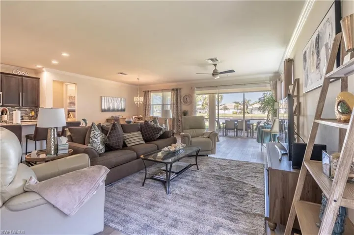 Living room with light hardwood / wood-style floors, crown molding, and ceiling fan with notable chandelier