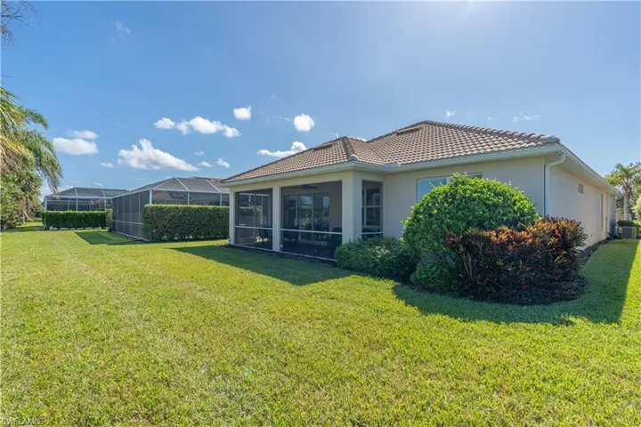 Rear view of property featuring a yard, a sunroom, glass enclosure, and central air condition unit