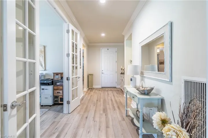 Hallway with ornamental molding, french doors, and light hardwood / wood-style flooring