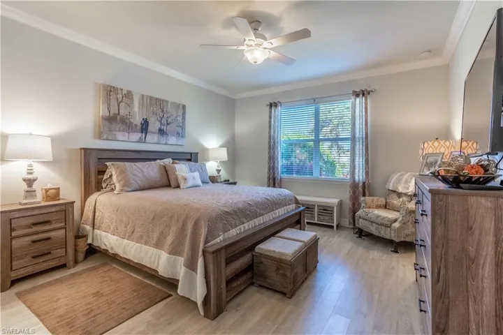 Bedroom featuring light hardwood / wood-style floors, crown molding, and ceiling fan