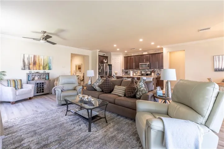 Living room featuring ornamental molding, light wood-type flooring, and ceiling fan