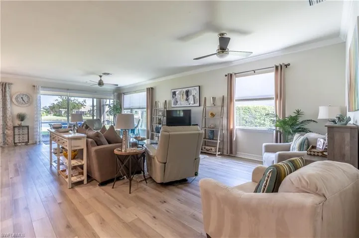 Living room featuring ornamental molding, ceiling fan, plenty of natural light, and light wood-type flooring