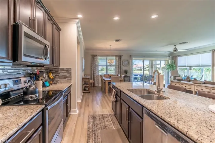 Kitchen featuring sink, light wood-type flooring, stainless steel appliances, dark brown cabinetry, and ornamental molding