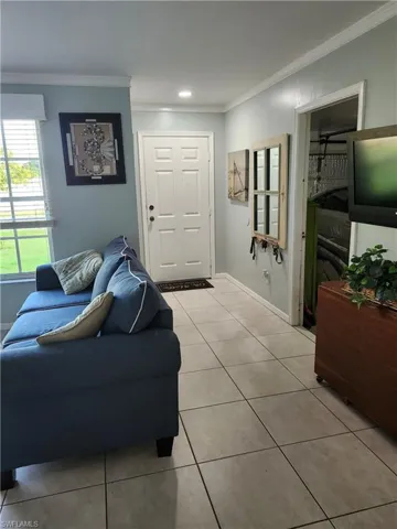 Living room featuring light tile patterned floors and crown molding