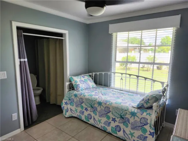 Tiled bedroom featuring ornamental molding, a closet, and ceiling fan
