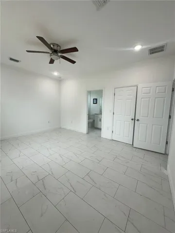 Unfurnished bedroom featuring light marble finish flooring, a ceiling fan, ensuite bath, recessed lighting, and a closet