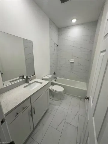 Full bathroom with light marble finish flooring, vanity, and tub / shower combination