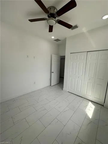 Unfurnished bedroom with light marble finish flooring, a closet, a ceiling fan, and recessed lighting
