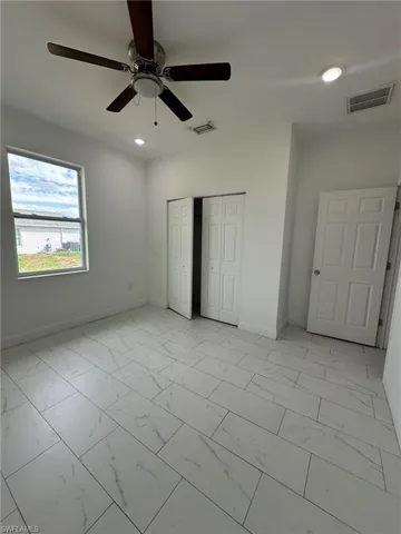 Unfurnished bedroom with light marble finish flooring, ceiling fan, a closet, and recessed lighting