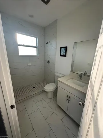 Full bath featuring vanity, light marble finish flooring, and a shower stall