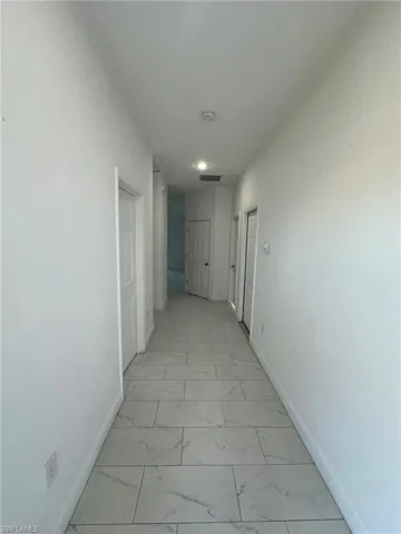 Hallway featuring light marble finish flooring and baseboards