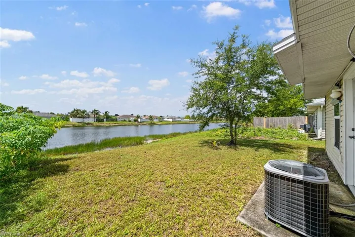Expansive backyard featuring a mature tree, natural grass, and a concrete patio
