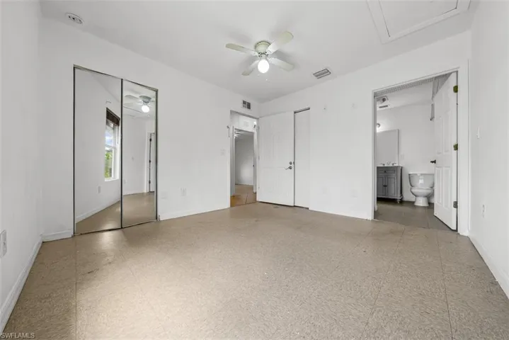 Spacious room featuring neutral flooring, white walls, a ceiling fan, and mirrored closet doors