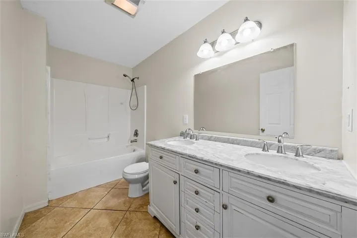 Bathroom 2 - Double vanity with white cabinetry and integrated sinks set in a stone countertop