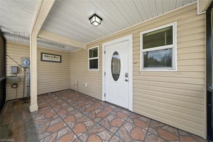 Covered front porch featuring beige horizontal vinyl siding