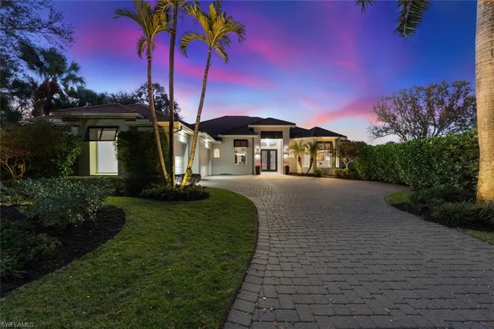 View of front facade with decorative driveway, an attached garage, stucco siding, and a lawn