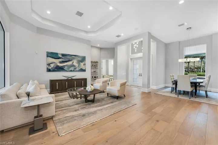 Living area featuring light wood-type flooring, recessed lighting, and a tray ceiling