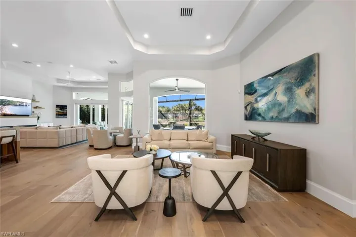 Living area with a ceiling fan, light wood-style flooring, recessed lighting, and a raised ceiling