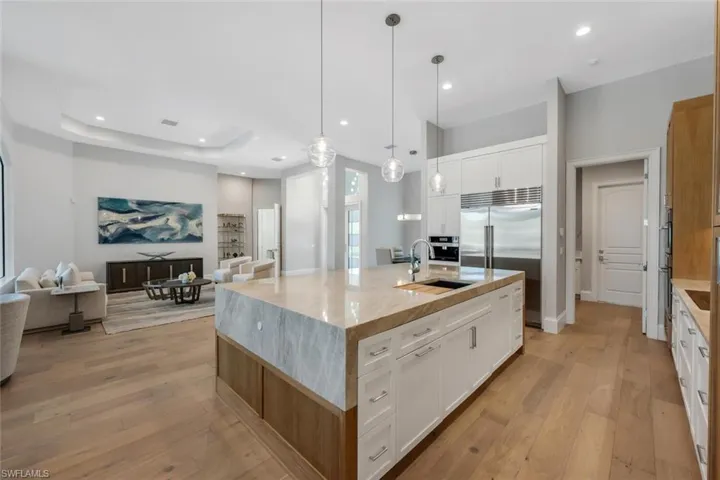 Kitchen with open floor plan, white cabinetry, light wood-type flooring, and a tray ceiling
