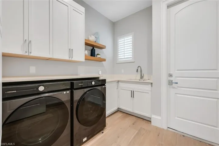 Laundry area featuring washing machine and dryer, light wood-type flooring, and cabinet space
